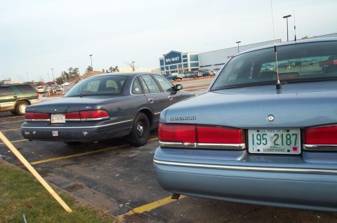 2001 Ford Crown Victoria - Two Ford Crown Victorias are parked in a lot with a Walmart in the background.