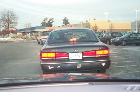 2001 Ford Crown Victoria - A dark sedan with a license plate ending in 7476 is seen from behind in a parking lot.