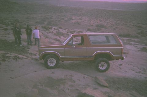 1983 Ford Bronco - A two-tone 1983 Ford Bronco is parked on a rocky hillside with several people standing nearby.