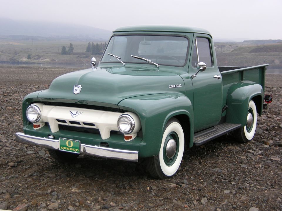 Green 1954 Ford F-250 pickup with whitewall tires and Oregon plate, parked on gravel, front three-quarter view