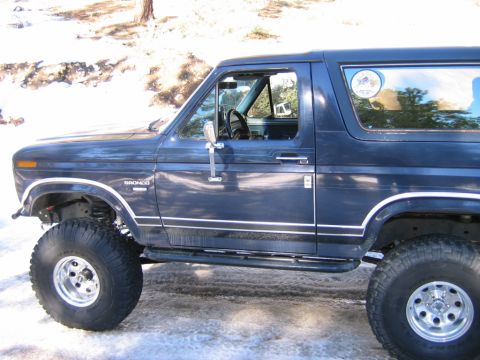 1985 Ford Bronco - A blue 1985 Ford Bronco is shown with its side profile, a lifted suspension and off-road tires.