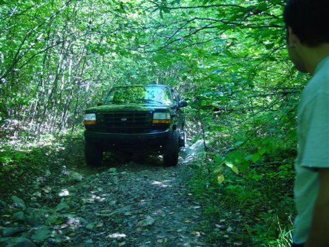 1996 Ford Bronco - A black 1996 Ford Bronco navigates a rocky, wooded path.