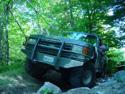1996 Ford Bronco - This 1996 Ford Bronco is shown tackling a challenging off-road path in a wooded area.