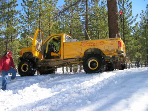 1985 Ford Bronco - A modified yellow truck with large tires sits in the snow with its doors and hood open.