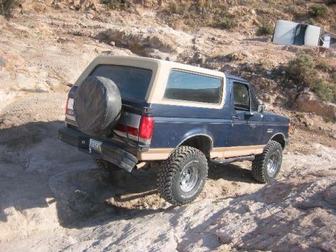1989 Ford Bronco - This 1989 Ford Bronco is navigating a challenging off-road terrain with steep inclines and loose rocks.