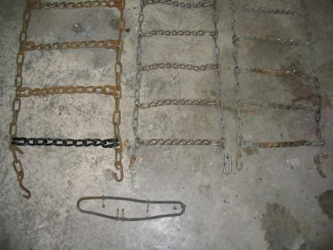 1979 Ford F-150 - A collection of tire chains and a tensioning tool are laid out on a concrete surface.
