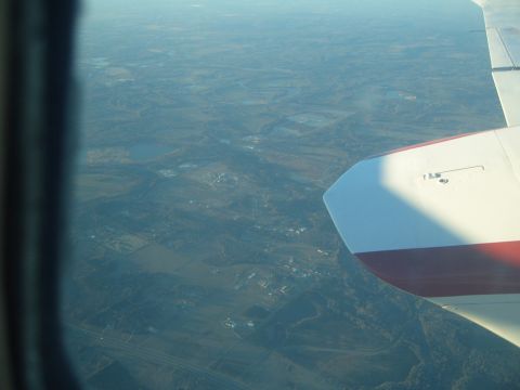 1988 Ford Bronco - View from an airplane window shows a wing and the landscape below, with a highway visible in the distance.