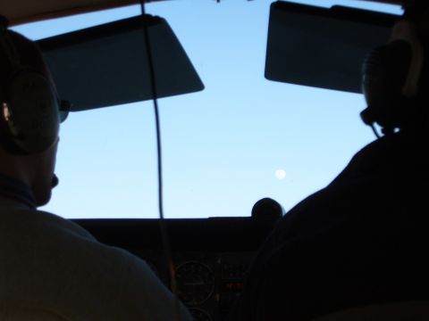 1988 Ford Bronco - Two people in headsets are inside a cockpit, looking out at the sky and moon.