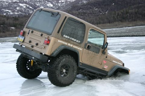 2003 Jeep TJ - A tan Jeep Wrangler TJ navigates through icy terrain, partially submerged in water.