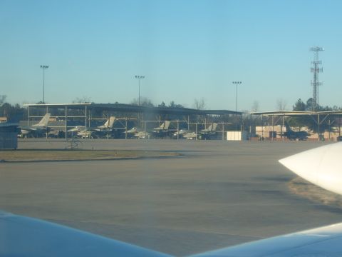 1988 Ford Bronco - Multiple fighter jets are parked under shelters on an airfield under a clear blue sky.