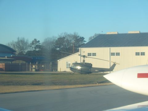 1988 Ford Bronco - A dark helicopter sits on the grass near a building, partially obscured by a white airplane.