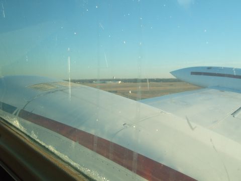 1988 Ford Bronco - View from an airplane window shows the wing and a distant airfield, with another aircraft visible.