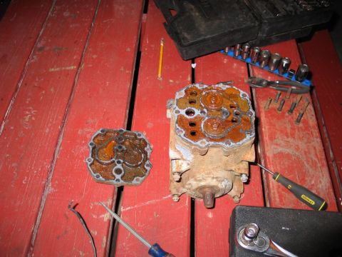 1989 Ford F-150 - Disassembled and corroded engine parts lie on a red wooden surface next to various tools.