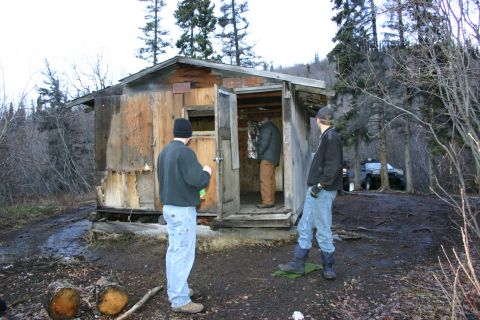 2003 Jeep TJ - An SUV is visible parked in a wooded area next to a run-down wooden cabin.
