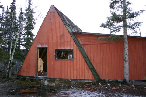 2003 Jeep TJ - Dilapidated A-frame structure in a wooded area, showing signs of neglect and disrepair.