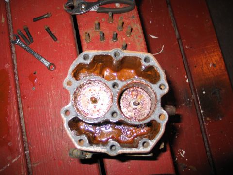 1989 Ford F-150 - A heavily corroded engine component sits on a red surface, surrounded by tools and disassembled parts.