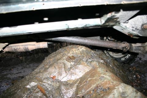 2003 Jeep TJ - Vehicle undercarriage on a rock, showing driveshaft and tire. Year unknown.