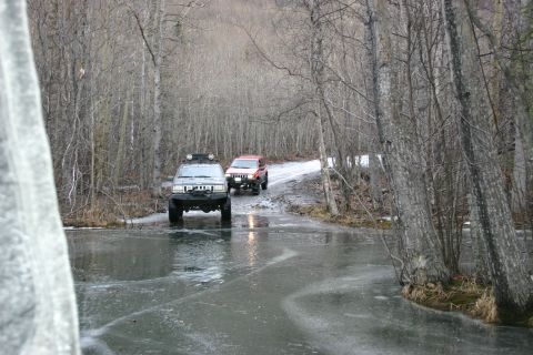 2003 Jeep TJ - Two SUVs navigate an icy path through a wooded area during winter.