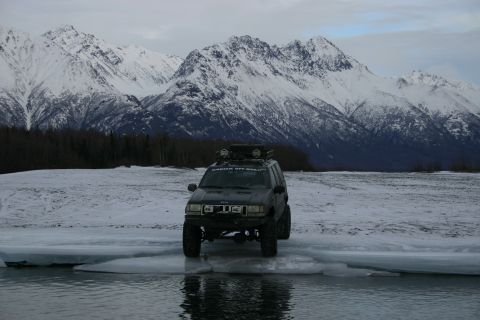 2003 Jeep TJ - Black Jeep Grand Cherokee navigates icy terrain with snow-capped mountains in the background.