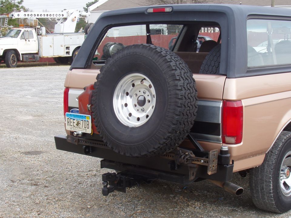Tan 1994 Ford Bronco rear with spare tire, tow hitch, and license plate REE 708