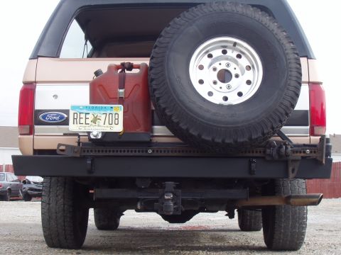1994 Ford Bronco - The rear of a 1994 Ford Bronco shows a spare tire, a red gas can, and a custom bumper with a tow hitch.