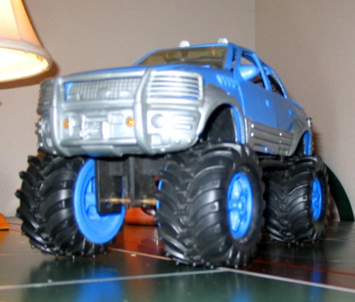 Blue toy monster truck with oversized tires and silver grille