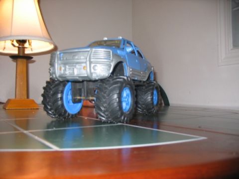 1978 Ford Bronco - A toy monster truck with large tires sits on a tiled surface next to a lamp.