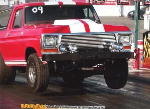 1979 Ford Bronco - A red 1978 Ford Bronco with white racing stripes is captured mid-air during a drag race.