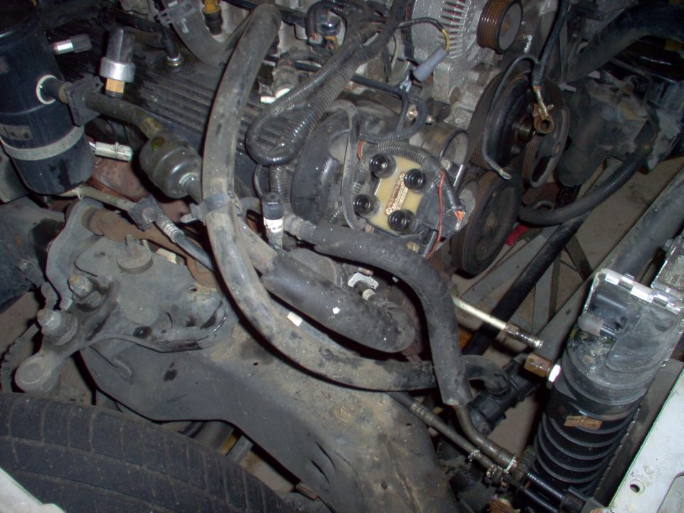 Dirty engine bay with belts, pulleys, hoses and brackets