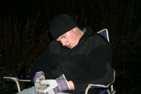2003 Jeep TJ - A person sleeps in a camping chair outdoors at night, wearing a beanie and jacket, with work gloves on.