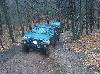 1995 Ford Bronco - A dark green Ford Bronco drives down a wooded path during autumn.
