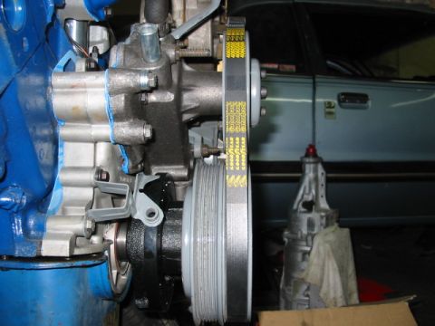 1985 Ford LTD Crown Victoria - Engine and transmission parts are visible, with a portion of a light blue car in the background.