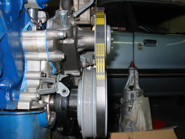 Close-up of engine components and a transmission with a light blue car door in the background