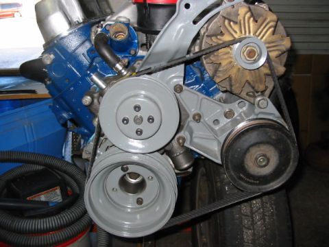 1985 Ford LTD Crown Victoria - This image shows a collection of engine components, including pulleys and belts, against a blue engine block.
