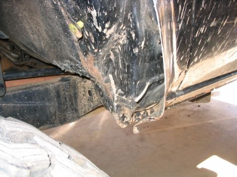 1986 Ford F-150 - The underside of a dirty vehicle, showing the frame and wheel well area.