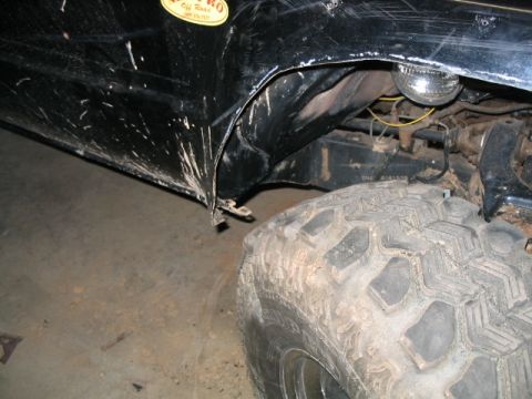 1986 Ford F-150 - Close-up view of the fender and tire on a black 1986 Ford F-150, showing mud splatter and modifications.