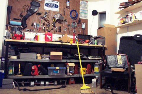 1985 Ford Crown Victoria LTD - A cluttered garage workbench displays tools, cleaning supplies, and a vintage Ford sign.