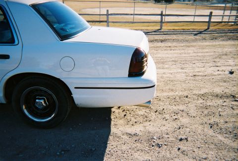 2000 Ford Crown Victoria - Rear view of a white 2000 Ford Crown Victoria parked on a dirt lot.