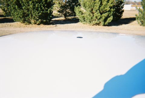2000 Ford Crown Victoria - Close-up of a white car's roof, showing a shadow and a small antenna base.