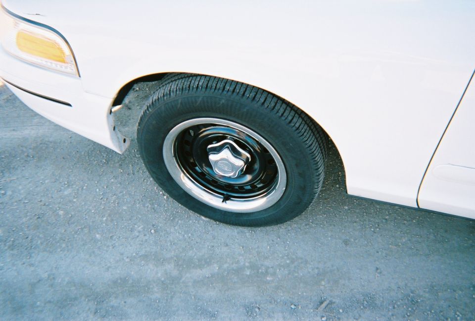 Front wheel and fender of a white 2000 Ford Crown Victoria