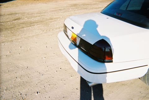 2000 Ford Crown Victoria - The rear of a white 2000 Ford Crown Victoria is shown from a low angle, with a shadow cast on the trunk lid.
