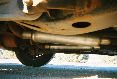 2000 Ford Crown Victoria - The underside of a vehicle reveals its exhaust system, including two mufflers and suspension parts.