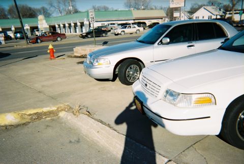 2000 Ford Crown Victoria - Two Ford Crown Victoria police cars are parked in a lot. The front of the car closest to the camera is visible.