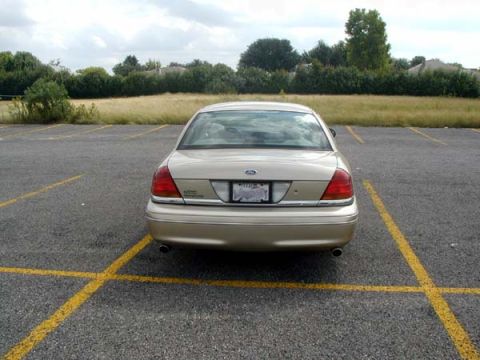 2000 Ford Crown Victoria - Rear view of a gold 2000 Ford Crown Victoria parked in a lot. The license plate is readable.