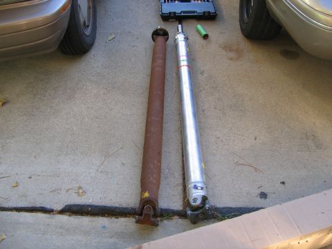 2000 Ford Crown Victoria - Comparison of a worn driveshaft with a replacement part, alongside a toolbox and vehicle parts.