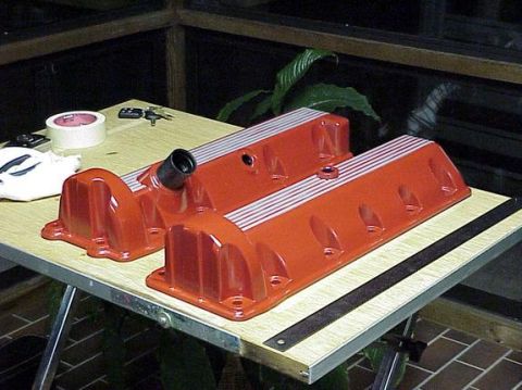 2002 Ford Mustang - Two orange valve covers with silver stripes are on a table next to tape and keys.