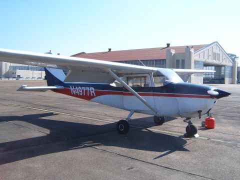 1988 Ford Bronco - A small aircraft with registration N4977R sits on an airport tarmac in front of a hangar.