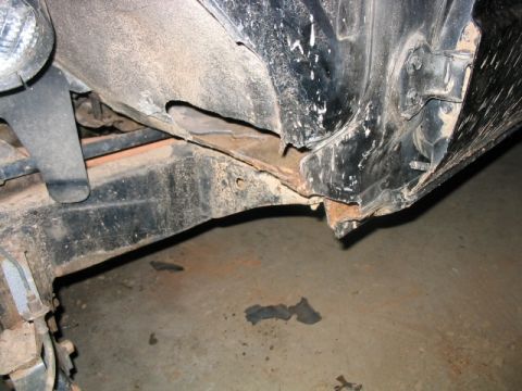 1986 Ford F-150 - Close-up view of a damaged and rusted truck frame and fender section.