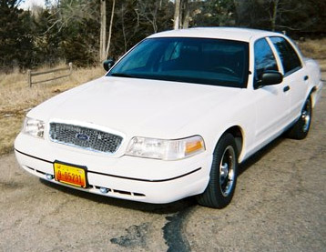 2000 Ford Crown Victoria - A white 2000 Ford Crown Victoria is shown from the front three-quarter angle. The grille design is indicative of the year.