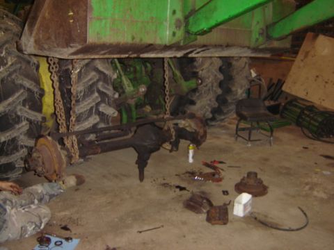 1992 Ford Bronco - A tractor's rear axle is disassembled and laid out on the garage floor for repair.
